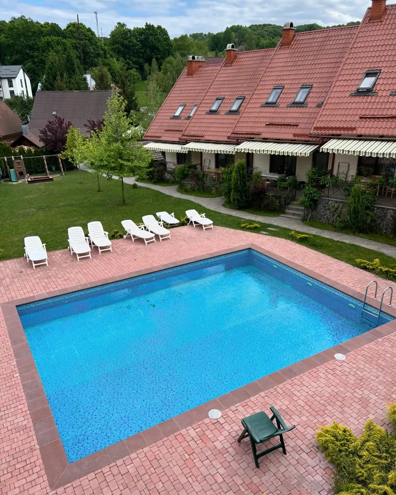 Napozóágyas medence a piros tetős apartmansor előtt
